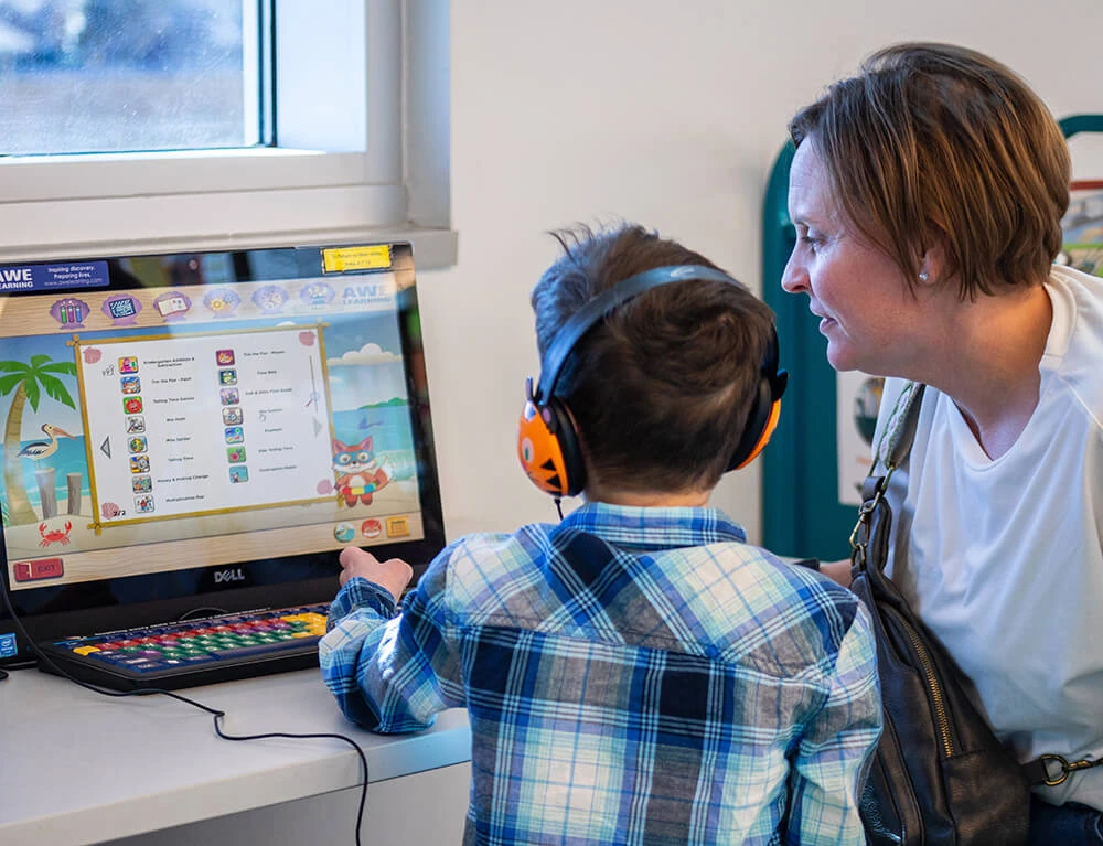 Woman helping child with computer Educational Program