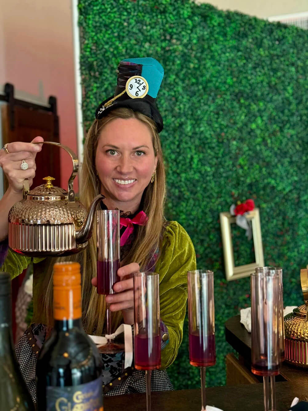 A woman dressed as the Cheshire Cat pours tea.