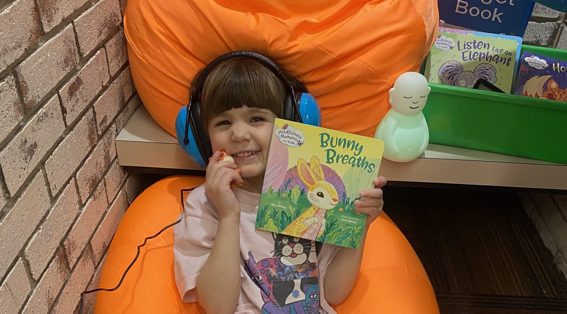 a girl is sitting on a bean bag chair holding a book in the library