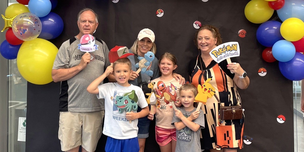 A family poses at the SOKC FanFest event in front of a festive backdrop.