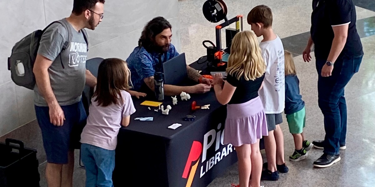 Parents and their four children gather around a registration table to sign-up for the PLS Summer Learning Challenge.